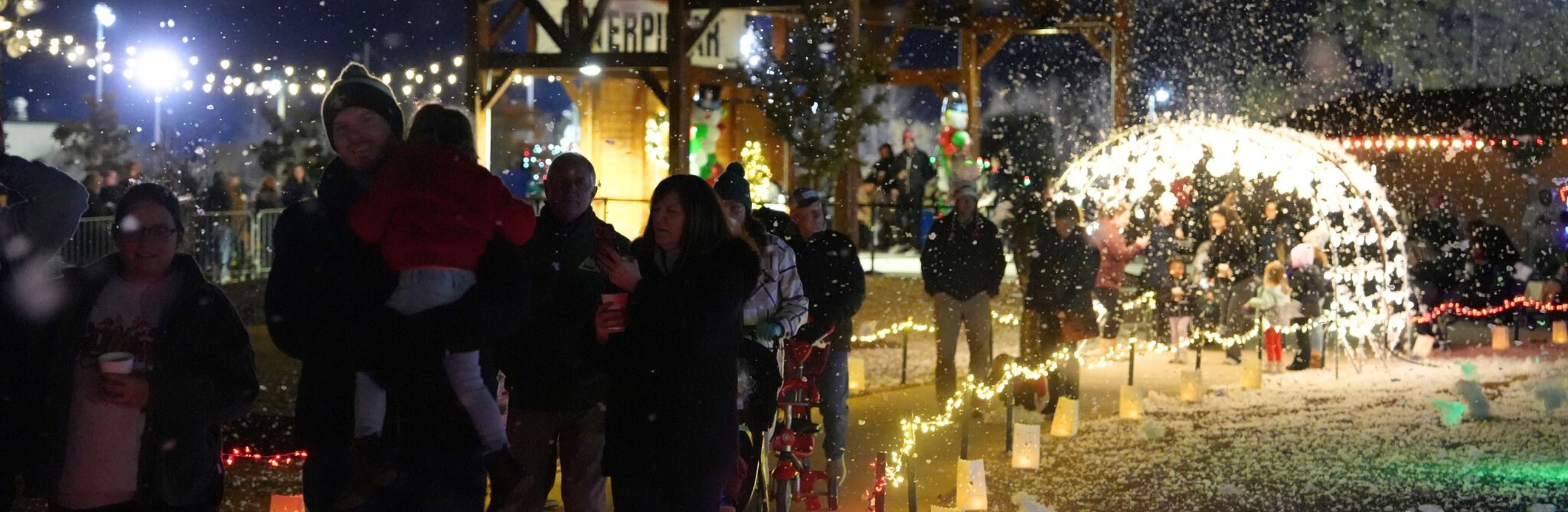 Families hold hot cocoa and smile while walking through Merry Municipal light show 